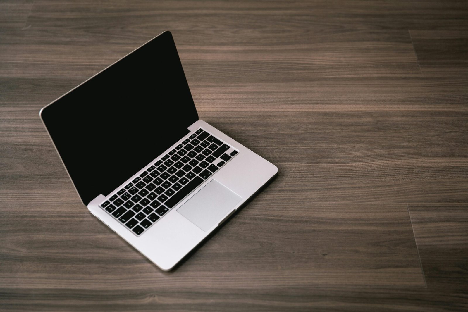 Sleek open laptop placed on a polished wooden floor, showcasing modern technology design.